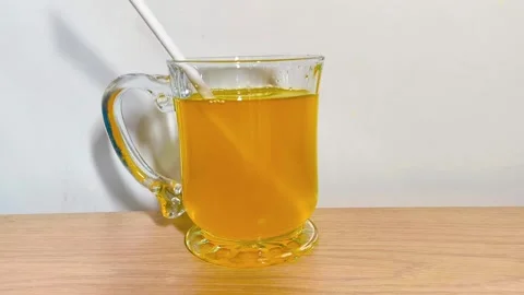 Inserting straw into a clear glass cup of orange juice with a handle on a w.. Video stock 318124585