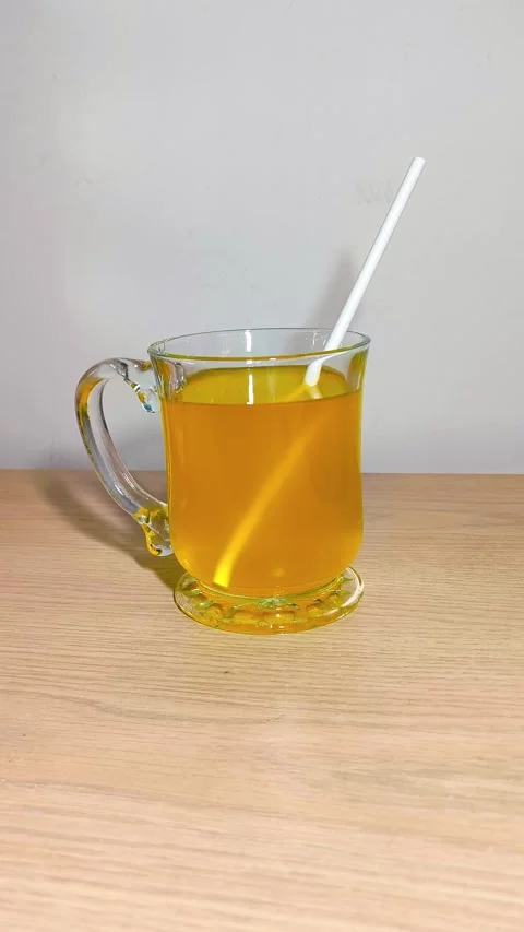 Inserting straw into a clear glass cup of orange juice with a handle on a w.. Stock Footage 318125304