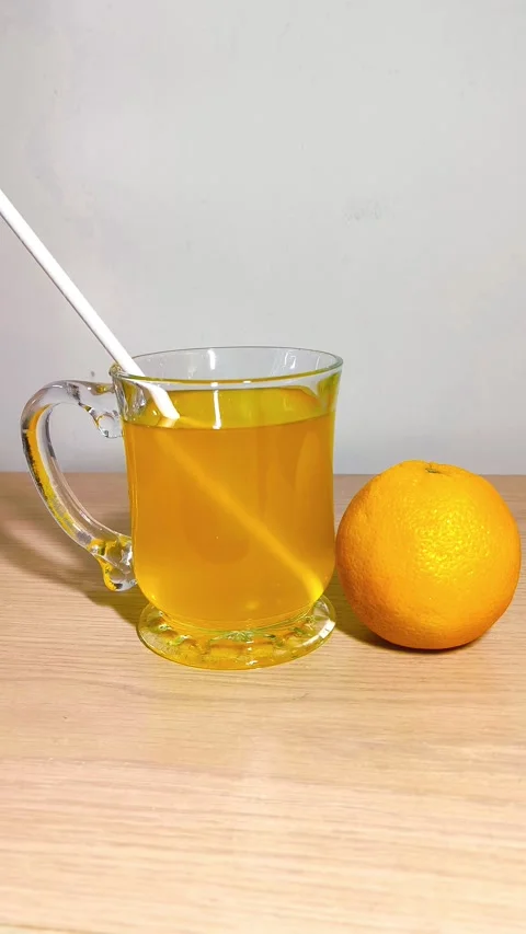 Inserting a straw into a clear glass cup of orange juice with a handle, pla.. Video stock 318128193