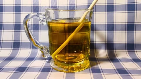 Inserting straw into clear glass of fruity apple juice on checkered plaid p.. Stock Footage 318126151