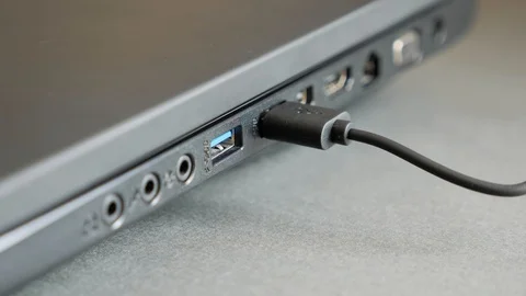 Inserting a USB cable into the side port of a laptop computer. Stock Footage 129811953
