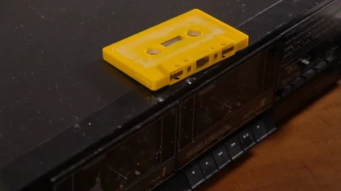 Inserting a yellow cassette tape (obsolete audio storage technology) into Stock Footage 113854391