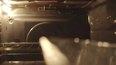 Inserting/placing in the oven a tray pan with marinated ribs for grilling in 4K Stock Footage 136130250