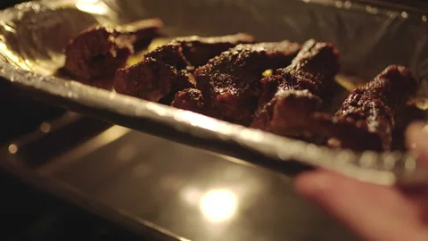 Inserting/placing in the oven a tray pan with marinated ribs for grilling in 4K Stock Footage 136134053