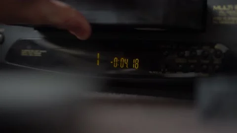 Inserts a video cassette into a VCR and presses the button and eject VHS Video stock 234407713
