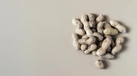 Inshell peanuts and scattered inshell peanuts on a light brown background Stock Photos