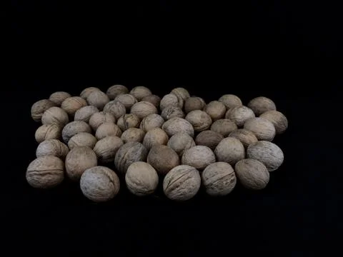 Inshell walnuts on a black background. Hard ripe nuts. Stock Photos