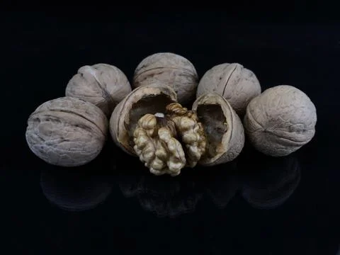 Inshell walnuts on a black background. Ripe walnut in a hard shell. Stock Photos