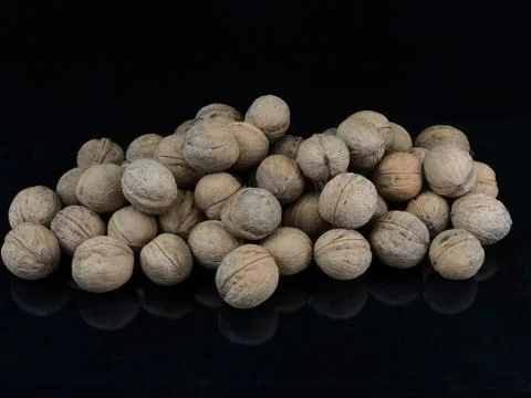 Inshell walnuts on a black background. Ripe walnut in a hard shell. Stock Photos