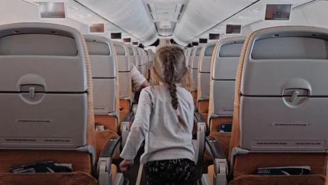 Inside airoplane, child run in airplane cabin, little cute girl walks aisle into Stock Footage 106361495
