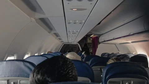 Inside airplane cabin, passengers seated in blue fabric chairs, flight attendant Video stock 315430439