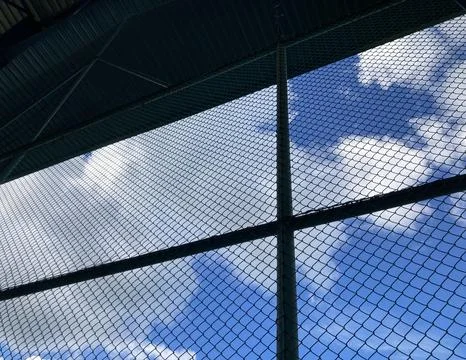 Inside the building which has a big steel net seeing through the bright blue sky Foto stock