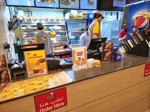 Inside a bustling crispy chicken outlet, staff in yellow and grey uniforms Stock-Fotos