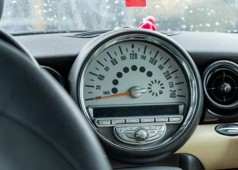 Inside a car, a speedometer shows the current speed amidst a gentle rain ou.. Stock Photos