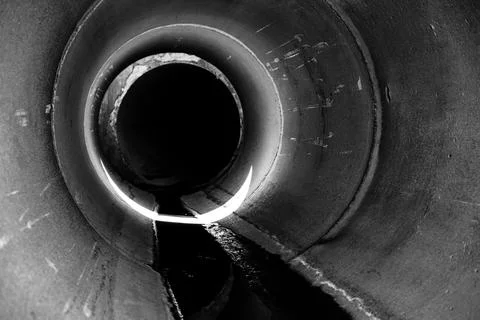 Inside a circular concrete drainage culvert with a trickle of water Stock Photos
