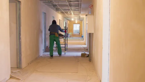 Inside construction site worker diligently pushing empty cart facilitating Stock Footage 268906439
