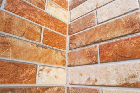Inside corner view of a modern orange and beige split-face decorative brick.. Stock Photos
