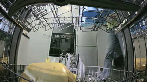 Inside dishwasher looking out at man's hand carefully stacking plates in. Stock Footage 54693621