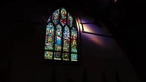 Inside empty dark church with lit up stained glass windows Stock Footage 169976176