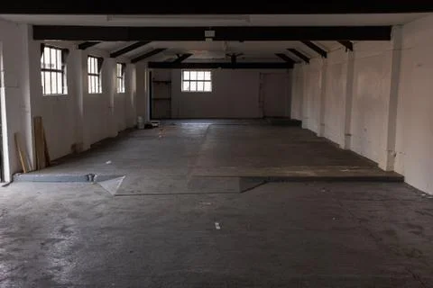 The inside of an empty farm building with white walls and black beams Stock Photos