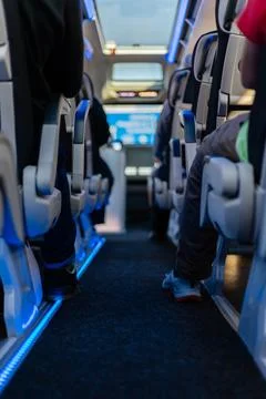 Inside a modern bus, passengers sit comfortably in spacious seats. Blue lig.. Stock Photos