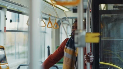 Inside modern tram young afro-american bearded man in coat standing in middle of Stock Footage 121475292
