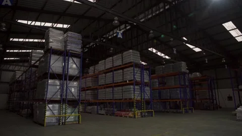 Inside modern warehouse Rows of shelves with boxes, lights turning going Stock Footage 133773111