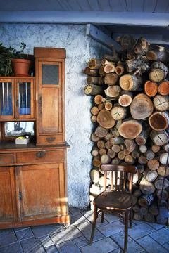 Inside the old hut, there is an old cupboard, a wooden chair, a stack of logs is Stock Photos