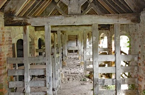 The inside of an old stable. Timber beams divide the internal space. Stock Photos