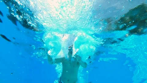 From inside the pool boy jumps into the pool and dives. Stock Footage 196217252
