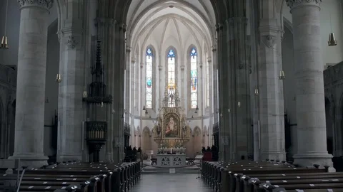 Inside praying hall of catholic cathedral with grey columns and stained glasses Stock Footage 98223135