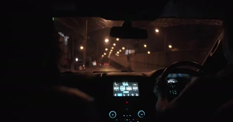 Inside rear view person driving car at night in city, handheld shot 動画素材 152813187