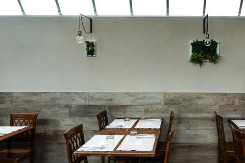 Inside a restaurant, set of table with chairs next to the wall with decoration Stock Photos