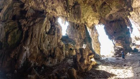 Inside a rocky cave with sunlight and lone traveler Stock Photos