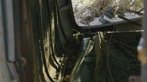 Inside a rusted blue green old car carcass on side with seat in the winter Vídeo Stock 255994229