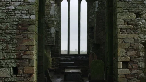 Inside Timoleague Abbey, arched stone windows frame a misty Irish horizon Stock Footage 308227016