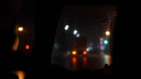 Inside view behind left of driver on wet windshield. The car goes on night road. Stock Footage 107999526