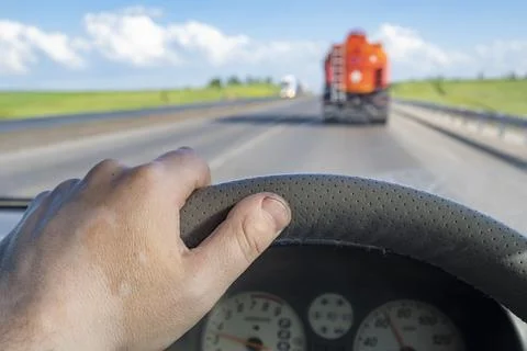 An inside view of a car driving behind a flammable fuel truck Stock Photos