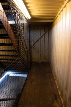 Inside view of converted shipping container with stairs and artificial neon i Fotos de archivo