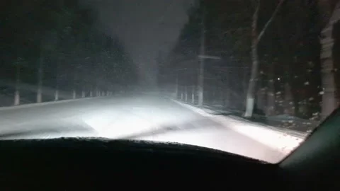 Inside view of front windshield of a driving in blizzard car. Empty night road. Video stock 144419621