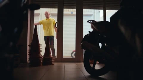 Inside view guy in yellow t-shirt closes garage with motorcycle. End of the Stock Footage 249435992