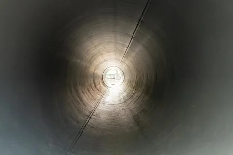 Inside view of a large metal pipe or tunnel with sunlight shining through the Stock Photos