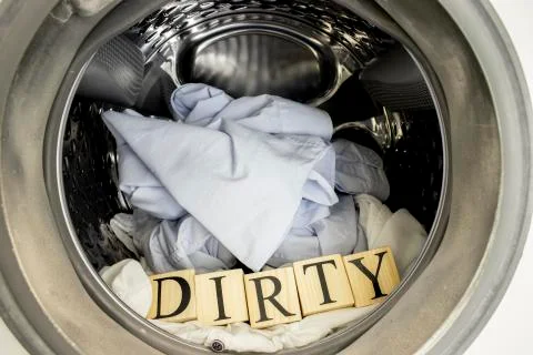 Inside the washing machine. Inside, there is laundry and text from wooden cubes. Stock Photos