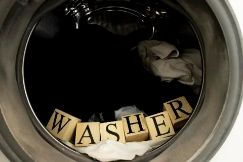 Inside the washing machine. Inside, there is laundry and text from wooden cubes. Foto stock