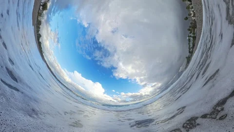 Inside-wave perspective creating a circular panorama of a beach with sea foam Stock Footage 293269026