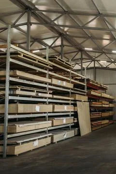 Inside a well-lit warehouse, sturdy wooden shelves are organized with neatly  Stock Photos