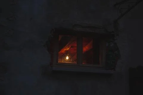 Inside, window lit, while outside the night is dark Stock Photos