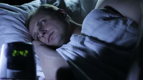 Insomnia. A man lying in bed and can not sleep 動画素材 101912643