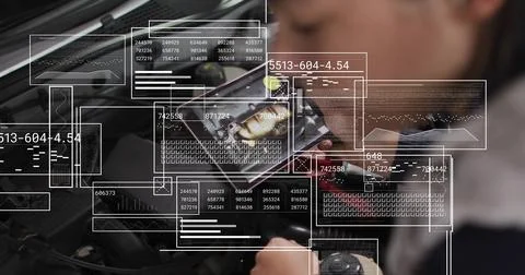 Inspecting auto tech in dark jacket leaning over engine bay in garage holding Stock Photos