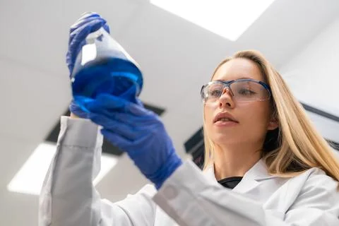 Inspecting blue chemical solution in laboratory flask during scientific research Fotos de archivo